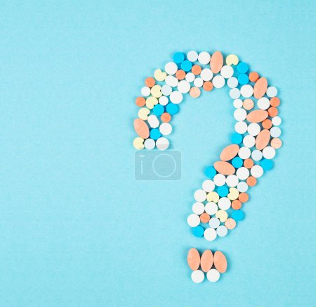 Photo for A question mark from laid out of medicine pills on blue background. - Royalty Free Image