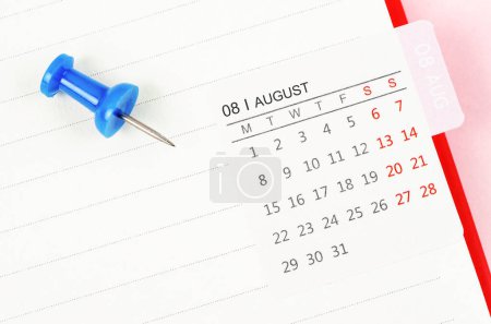 Photo for Mini August calendar on a white note book with push pin on pink colour background. - Royalty Free Image