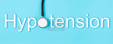 Téléchargez les photos : Hypotension text and medical stethoscope on blue background, Screening for Hypotension disease concepts. - en image libre de droit
