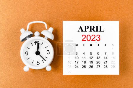Foto de April 2023 Monthly calendar for the organizer to plan 2023 year with alarm clock on yellow background. - Imagen libre de derechos