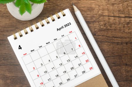 April 2023 desk calendar for 2023 with pencil on wooden background.