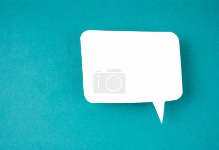 White speech bubble shaped post it note on green background with copy space.