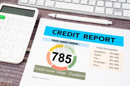 Credit score report and calculator with computer keyboard on the desk.