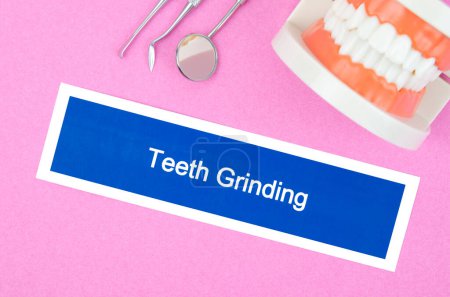 Modèle de dents avec broyage des dents, maladie dentaire sur fond rose.
