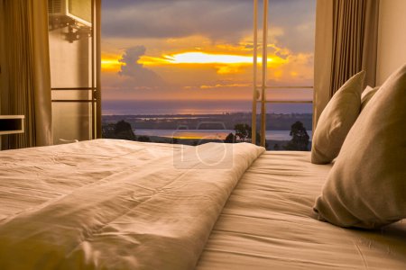 Interior minimalista del dormitorio con vista al mar en la hora de la puesta del sol.