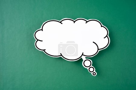 Photo for White speech bubble shaped post it note on green background with copy space. - Royalty Free Image