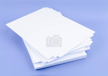 Téléchargez les photos : Empilement de feuilles A4 vierges sur fond bleu. - en image libre de droit