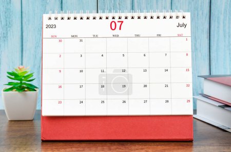 Photo for July 2023 Monthly desk calendar for 2023 year with the books on blue wooden background. - Royalty Free Image