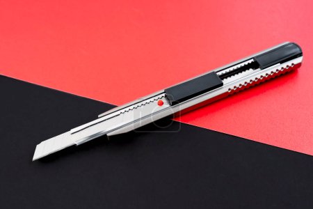 Foto de Un cuchillo de corte o un cuchillo de papelería sobre fondo negro y rojo. - Imagen libre de derechos