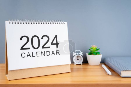 2024 Kalender auf Holztisch und grauem Hintergrund. Neujahrspläne für 2024.