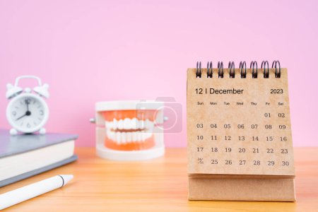 Téléchargez les photos : Calendrier mensuel de bureau de décembre pour 2023 ans et prothèses dentaires modèles sur la table avec réveil. Concepts de santé dentaire. - en image libre de droit