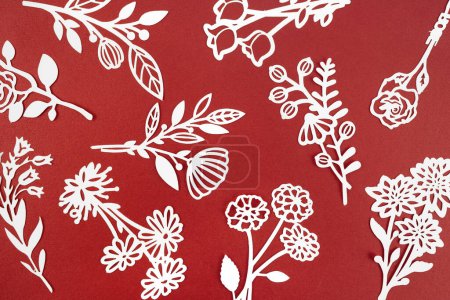 Photo for White paper cut plants leaves on red color background. - Royalty Free Image