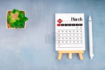 2024 März Kalenderblatt und Stift mit Pflanzentopf auf blauem Holzgrund.