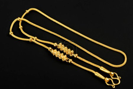 Gold necklace on a black color background.