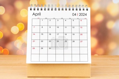 April 2024 desk calendar on wooden table with gold light bokeh background. New Year Concept.