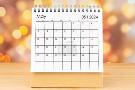 Mai 2024 Schreibtischkalender auf Holztisch mit goldenem Licht Bokeh Hintergrund. Neujahrskonzept.