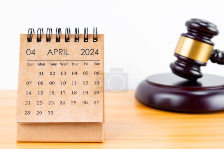 Calendrier de bureau pour avril 2024 et marteau du juge sur la table de travail.