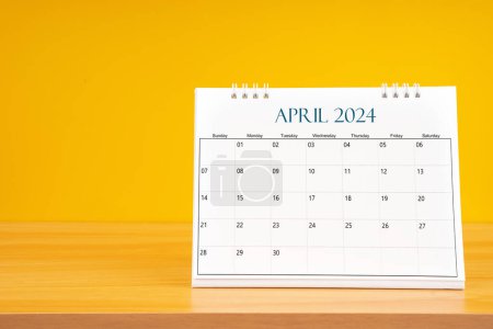 April 2024, Monthly desk calendar for 2024 year on wooden table with yellow background.