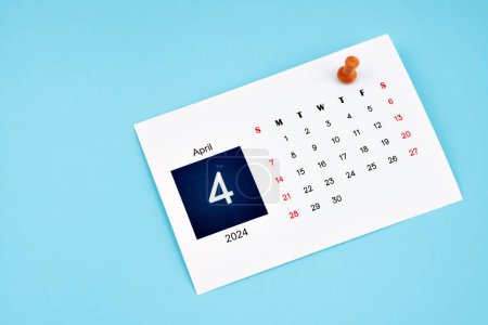 Photo for April 2024 calendar page with push pin on blue color background. - Royalty Free Image
