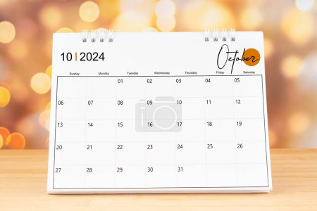 October 2024 desk calendar on wooden table with gold light bokeh background. New Year Concept.