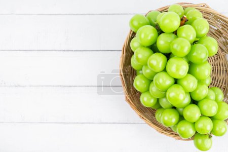 Fresh shine Muscat Grape in basket on white wooden background.