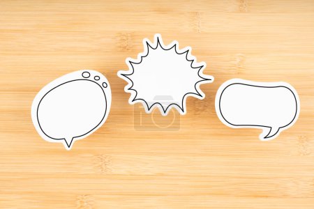 White chat bubbles on wooden background. Horizontal composition with copy space.