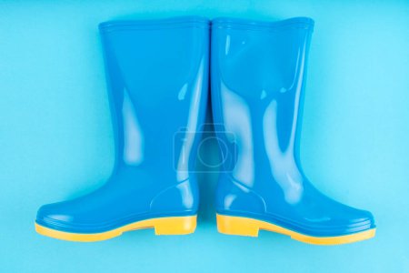 Pair of blue rubber boots on blue color background,