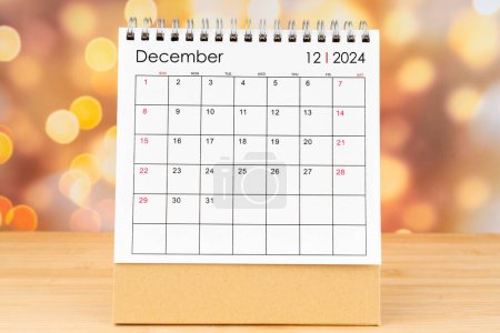 Dezember 2024 Schreibtischkalender auf Holztisch mit goldenem Licht Bokeh Hintergrund. Neujahrskonzept.