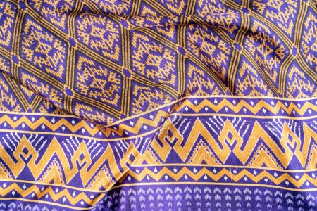 Thai Northeast Sarong, Handwoven Mudmee or Ikat silk fabric in blue pattern in vintage tone background. Thai traditional clothing.