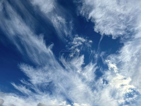 Hoch aufragende Zirruswolken federn über einen strahlend blauen Himmel und rufen ein Gefühl der Ruhe und ausgedehnten Atmosphäre hervor