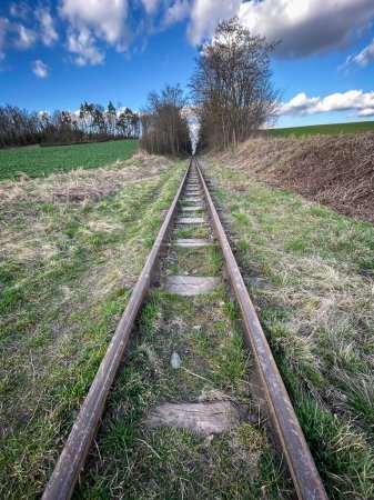 Simetría ferrocarril de vía estrecha en la campiña primaveral bajo el cielo azul - República Checa, Europa.