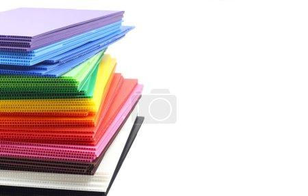 Stack of colorful corrugated plastic sheets isolated on white background.