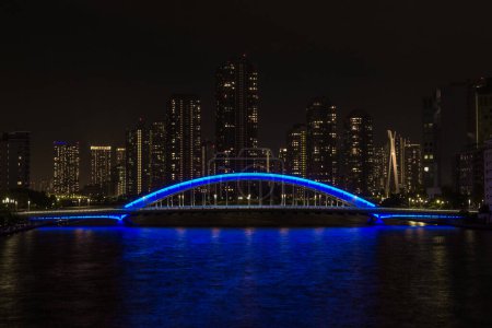 Foto de Night view of the Eitai Bridge over the Sumidagawa river, with tall buildings behind, Tokyo, Japan. - Imagen libre de derechos
