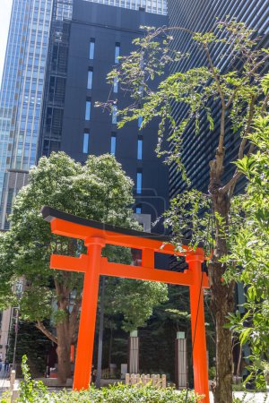 Photo for Red torii gate with modern tall buildings behind. Fukutoku jinja shrine, Tokyo, Japan. - Royalty Free Image