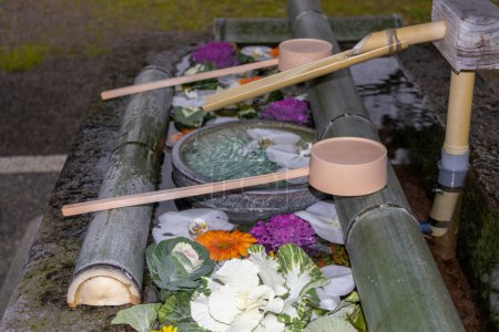 Lavabo à mains, chouzubachi en japonais, avec fleurs et pétales, au sanctuaire, Kanazawa, Japon. Traduction : flux spirituel.