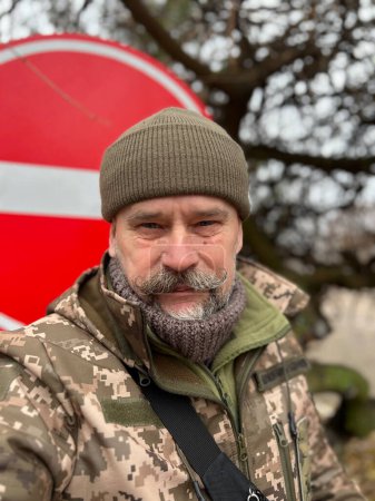 Foto de Retrato de un anciano soldado ucraniano con bigote en el fondo de una señal de tráfico prohibitiva - Imagen libre de derechos
