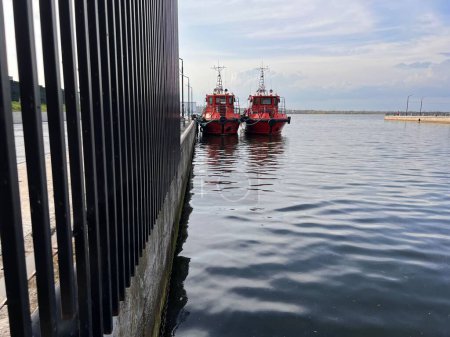 Foto de Dos barcos de bomberos rojos están amarrados en el muelle del puerto fluvial - Imagen libre de derechos