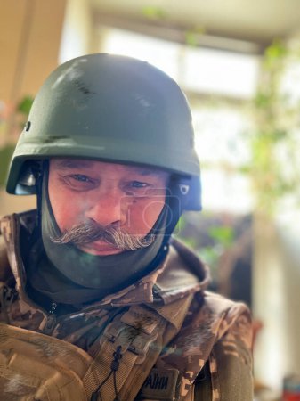 Foto de Un soldado anciano con bigote y casco protector, camuflaje uniforme militar durante la guerra en Ucrania - Imagen libre de derechos