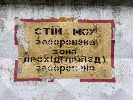 Foto de Placa en la pared con pintura pelada. Traducción: "Stop fenced zone pass fenced". Guerra en Ucrania - Imagen libre de derechos