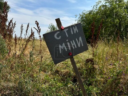 Foto de Peligro firma mina en ucraniano cerca de un campo agrícola durante la guerra en Ucrania, traducción: "Stop Mine" - Imagen libre de derechos