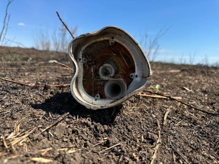 Foto de Elemento explosivo deformado del proyectil de cohete yace en el campo ucraniano durante la guerra - Imagen libre de derechos