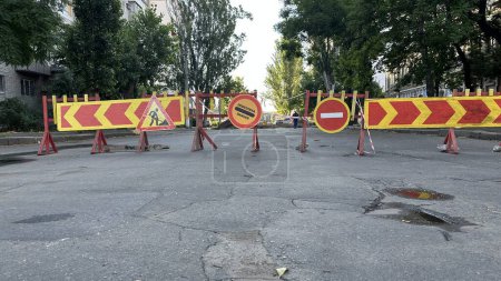 Foto de Barrera con señales de desvío en la calle de la ciudad después de disparos de cohetes y daños al oleoducto de agua durante la guerra en Ucrania - Imagen libre de derechos