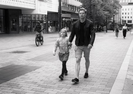 Foto de A father and his daughter are walking in a fast pace on the street. They obviously have some important business together. - Imagen libre de derechos