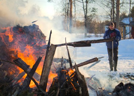 Photo for A senior man seems to be pleased with the results of his work with the bonfire. These bonfires are traditionally burned in the Norhtern parts of Finland during Easter time. - Royalty Free Image