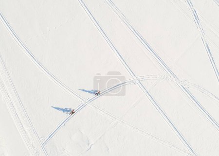 Photo for Two bikers are starting their bicycle trip on the frozen lake. The bright sunlight casts their shadows on the snow. - Royalty Free Image