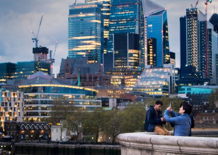 Photo for A tourist is photographing the evening view of London. She is using her mobile phone. - Royalty Free Image