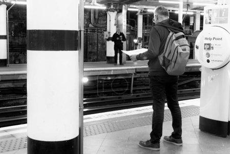 Photo for A man is reading a map at the underground station by the help point. - Royalty Free Image