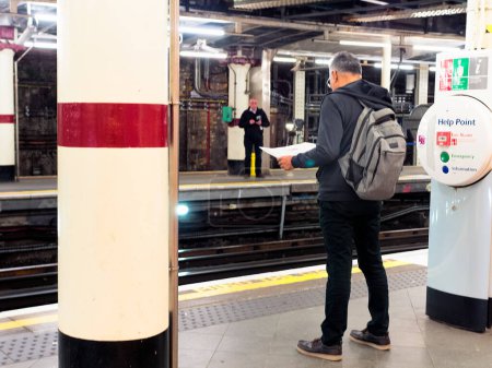 Photo for A man is reading a map at the underground station by the help point. - Royalty Free Image