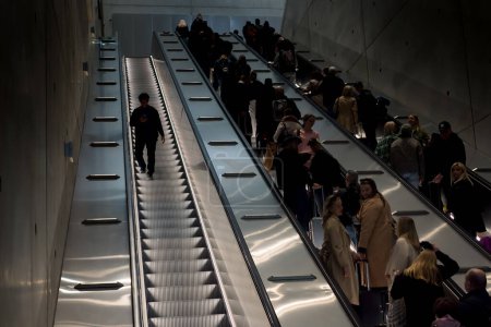 Photo for Only one person is going downwards in the escalator. There are quite a lot of people going upwards. - Royalty Free Image