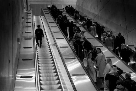 Photo for Only one person is going downwards in the escalator. There are quite a lot of people going upwards. - Royalty Free Image